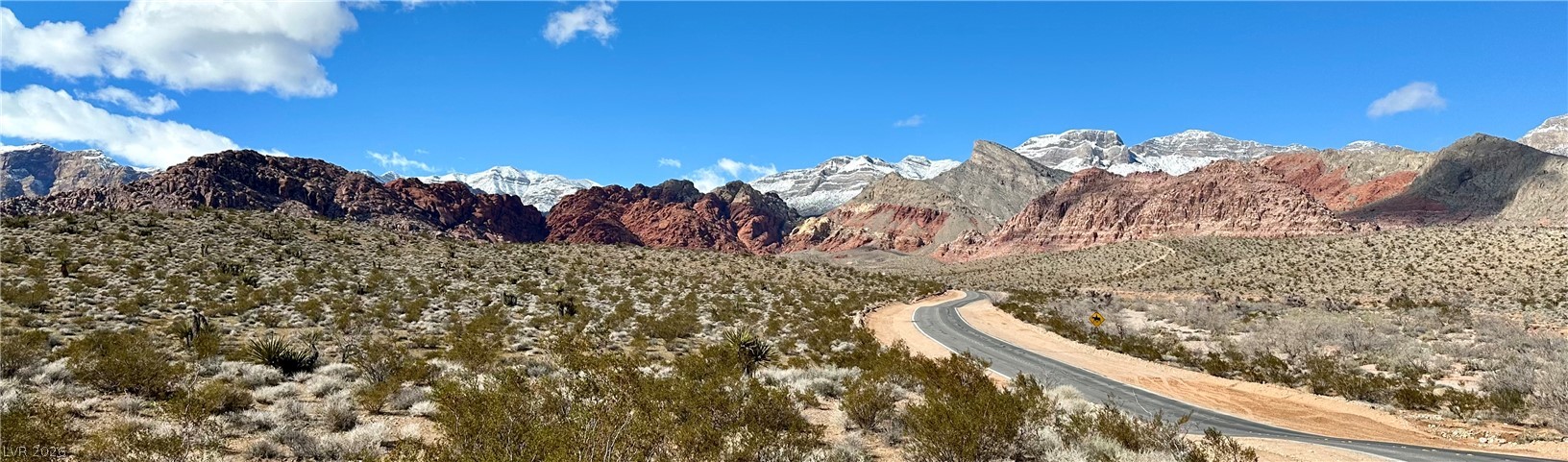 10959 Pumpkin Ridge Avenue Las Vegas, NV 89135 - Photo 45 of 51 Red Rock Canyon scenic landscape of desert flora, framed by colorful mountains under a wide-open sky.