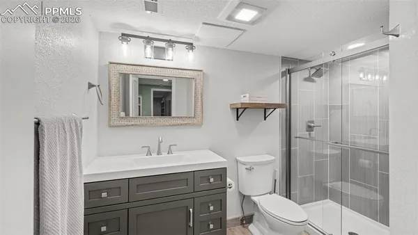 a bathroom with a toilet a sink a glass door a shower and a mirror