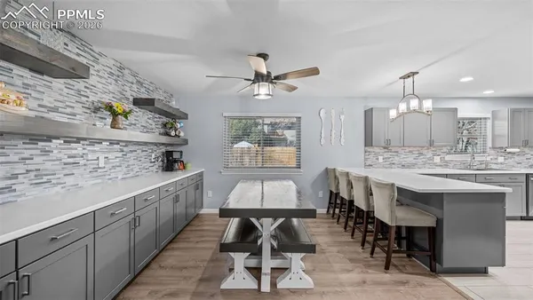 a kitchen with stainless steel appliances granite countertop a stove a sink dishwasher and a dining table with wooden floor