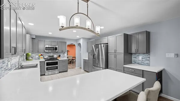 a kitchen with kitchen island stainless steel appliances a stove refrigerator dining table and chairs