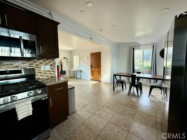 a kitchen with stainless steel appliances granite countertop a stove top oven a sink a dining table and chairs