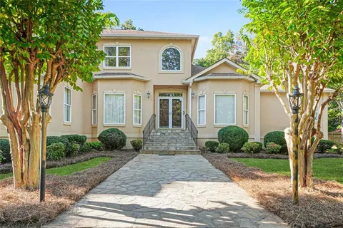 a view of a brick house with a large windows plants and large trees