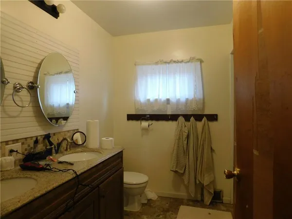 a bathroom with a granite countertop sink toilet and a mirror