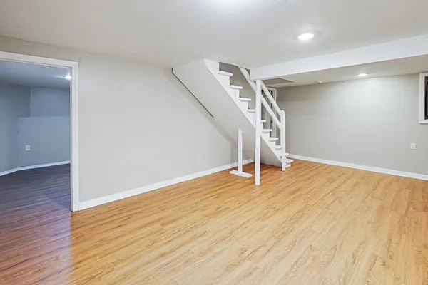 a view of an empty room with wooden floor and stairs
