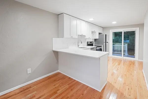 a kitchen with a sink a stove cabinets and wooden floor
