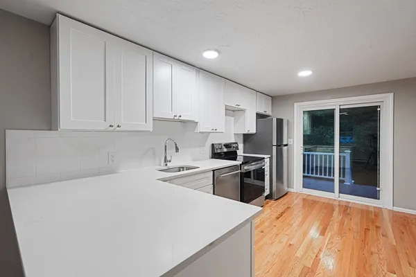a kitchen with stainless steel appliances a stove top oven a refrigerator a sink and dishwasher with wooden floor