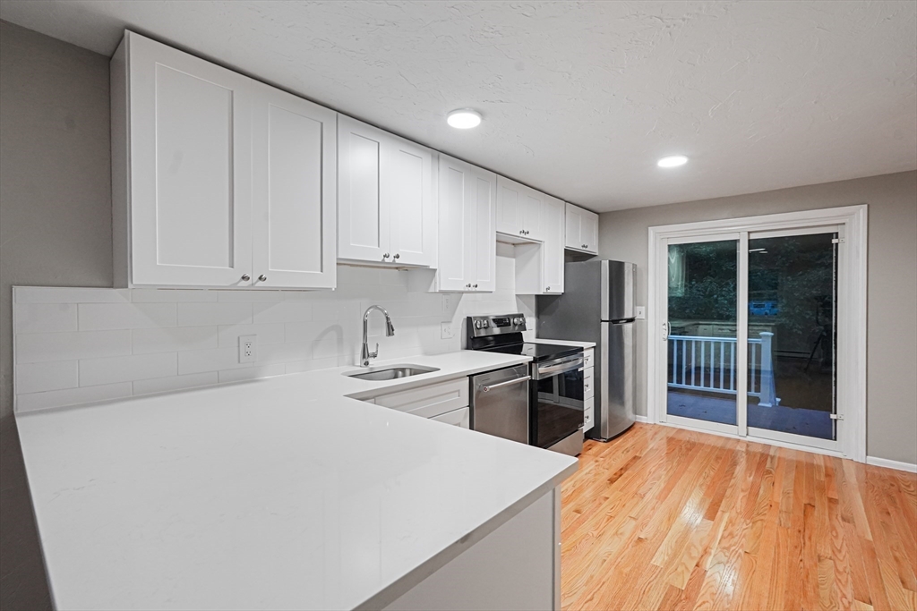 7 Debra Lane, Unit 1 Bellingham, MA 02019 - Photo 7 of 25 a kitchen with stainless steel appliances a stove top oven a refrigerator a sink and dishwasher with wooden floor