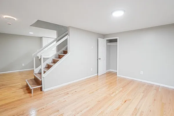a view of an empty room with wooden floor and stairs