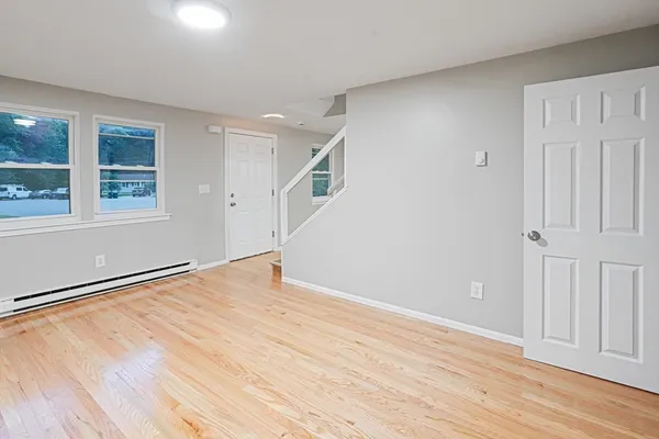 a view of an empty room with wooden floor and a window