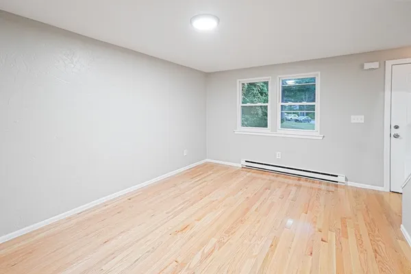 an empty room with wooden floor and windows