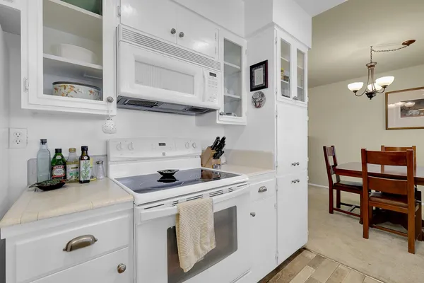 a kitchen with stainless steel appliances a white stove top oven and white cabinets