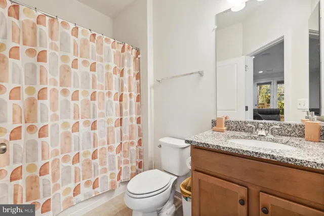 a bathroom with a granite countertop toilet a sink and a mirror