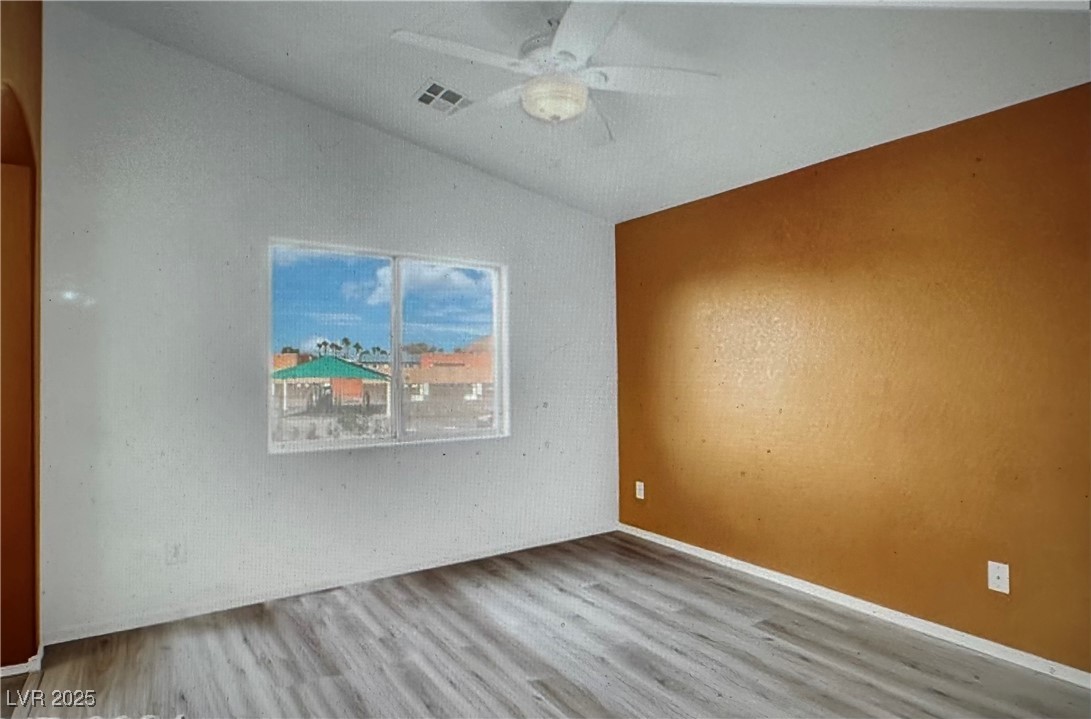 5512 East Jackpot Winner Lane, Unit 102 Las Vegas, NV 89122 - Photo 9 of 15 Empty room with vaulted ceiling, a ceiling fan, and wood finished floors