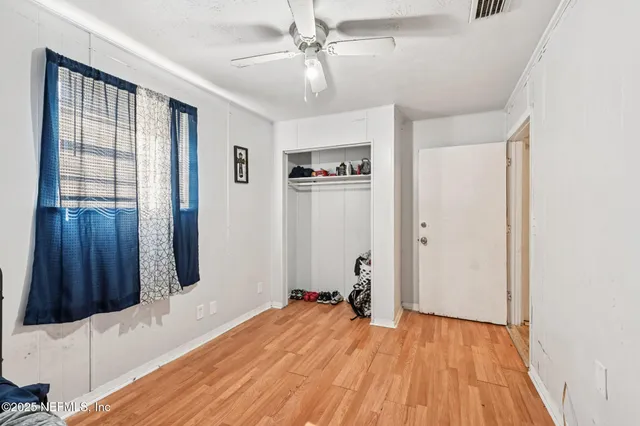 a view of a bedroom with wooden floor and a ceiling fan