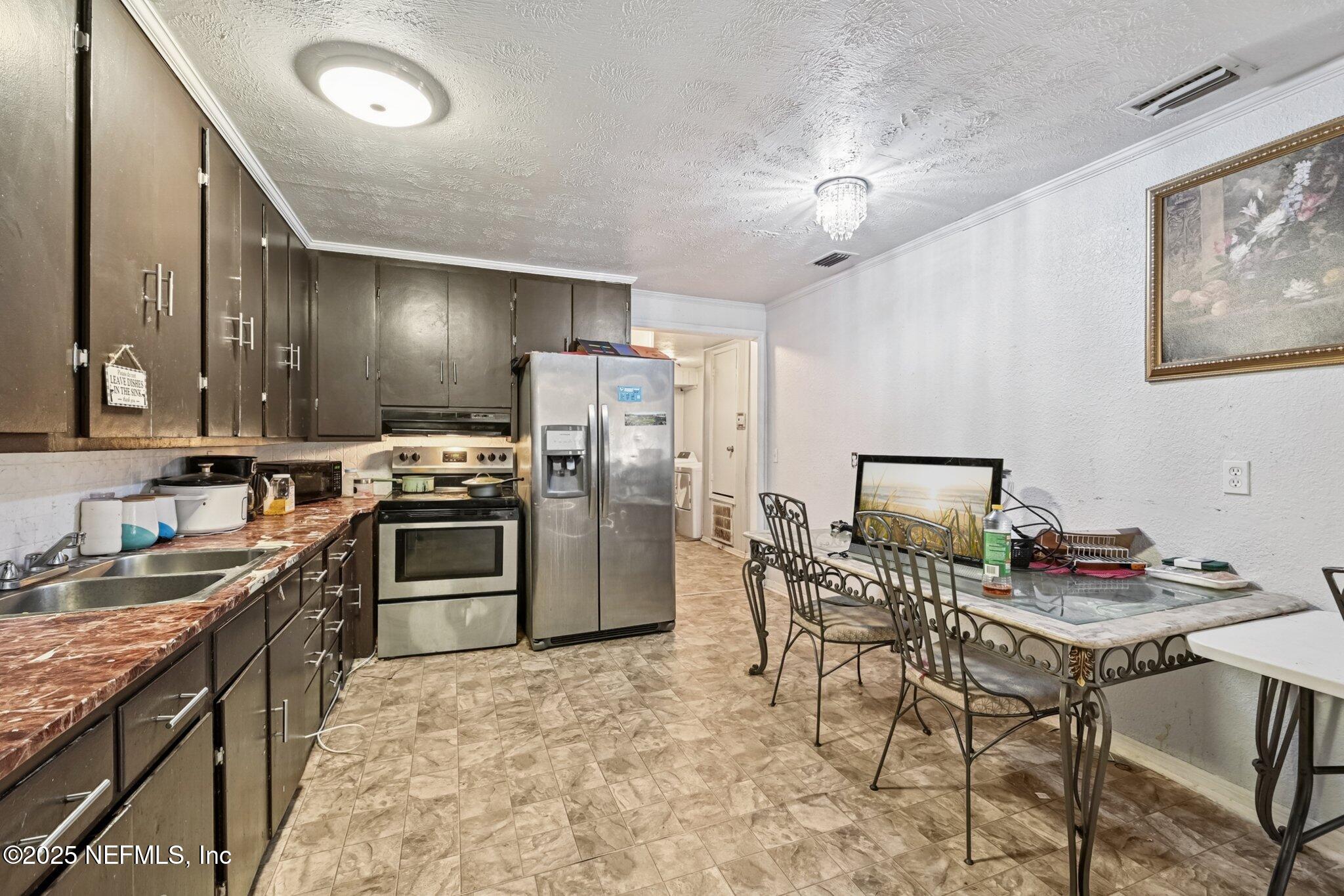5635 Atlee Avenue Jacksonville, FL 32205 - Photo 10 of 31 a kitchen with a refrigerator a stove a sink dishwasher with a dining table and chairs