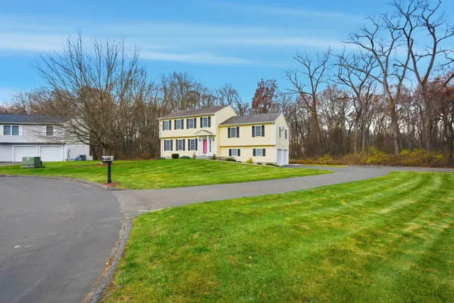 a view of a house with a big yard and large trees