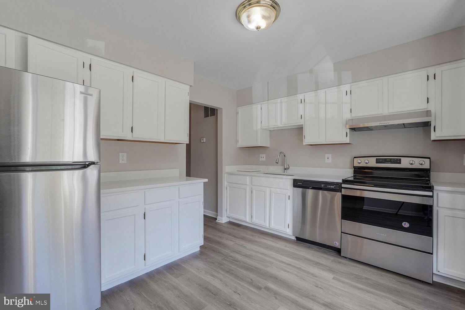 7314 Eggar Woods Lane Springfield, VA 22153 - Photo 6 of 23 a kitchen with cabinets stainless steel appliances and wooden floor