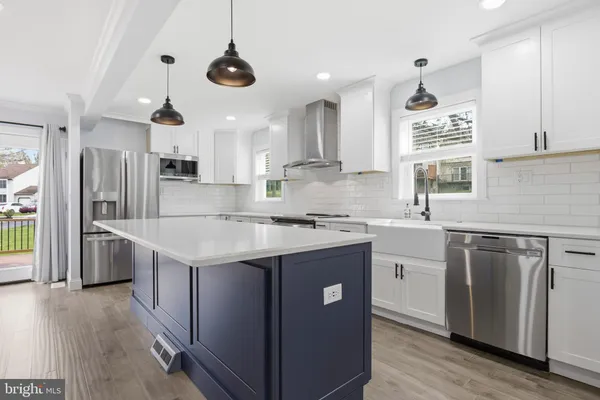 a kitchen with stainless steel appliances granite countertop a sink a stove a refrigerator and island with wooden floor