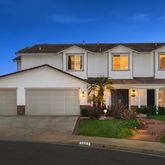 a view of a white house with a small yard and plants
