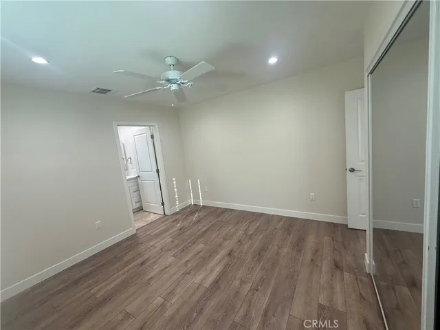 an empty room with wooden floor and fan