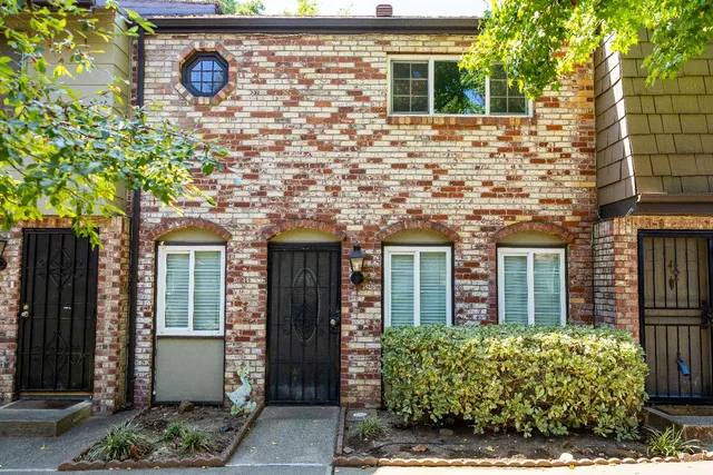 front view of a brick house with a large window and potted plants