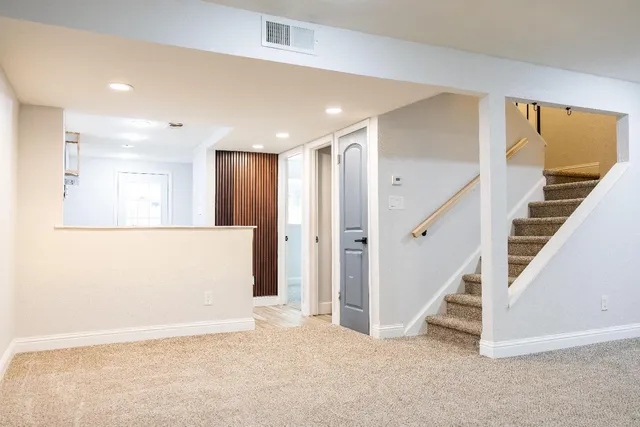 a view of an empty room with wooden floor and stairs