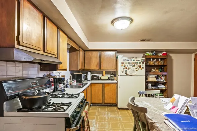 a kitchen with stainless steel appliances granite countertop a stove and a view of living room