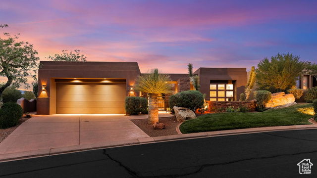 View of front of property featuring stucco siding, an attached garage, a front yard, and concrete driveway