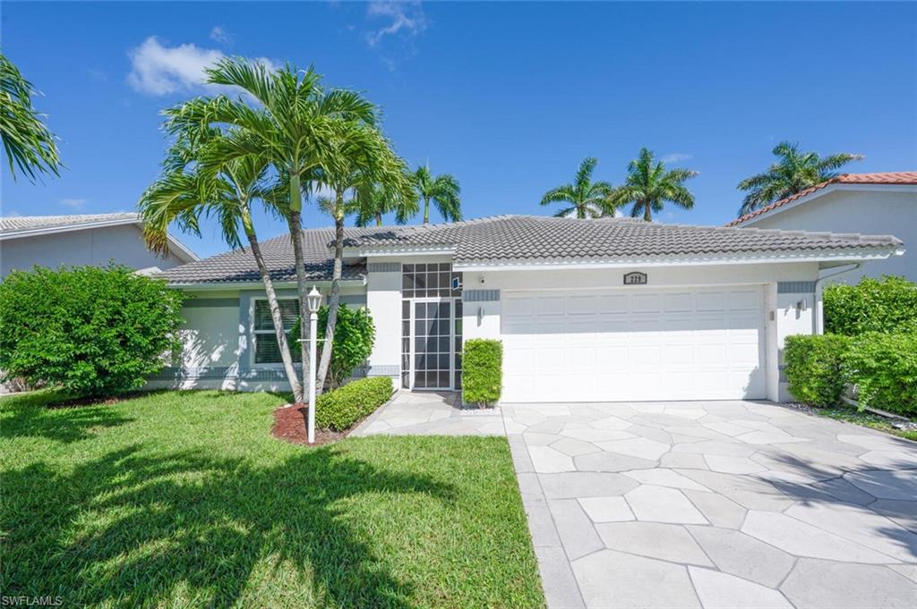 229 Countryside Drive Naples, FL 34104 - Photo 1 of 44 a view of a white house with a yard and potted plants