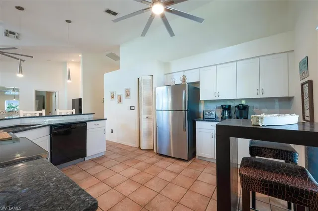 a open kitchen with stainless steel appliances granite countertop a sink dishwasher stove top oven a dining table and chairs with wooden floor