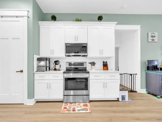 a kitchen with stainless steel appliances a stove a microwave and white cabinets