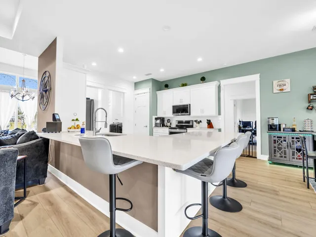 a living room with stainless steel appliances furniture a dining table and kitchen view