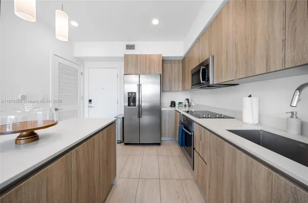 a kitchen with stainless steel appliances granite countertop a sink a stove a refrigerator a washer dryer and cabinets