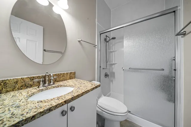 a bathroom with a granite countertop sink toilet and shower