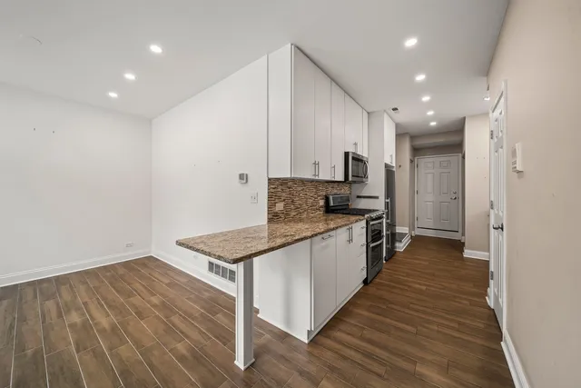 a large kitchen with stainless steel appliances granite countertop a stove and a sink