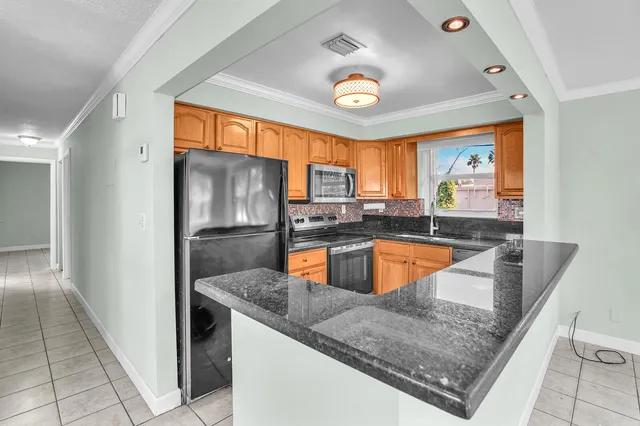 a kitchen with stainless steel appliances granite countertop a sink a refrigerator and a granite counter tops with a large window