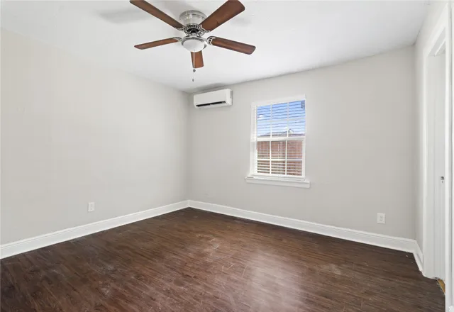 an empty room with wooden floor ceiling fan and windows