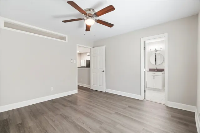 an empty room with wooden floor and a ceiling fan