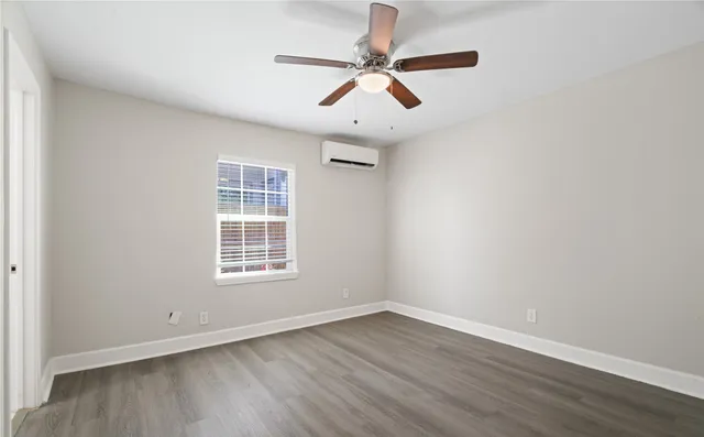 an empty room with wooden floor ceiling fan and windows