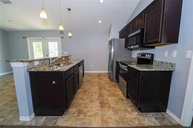 a kitchen with stainless steel appliances granite countertop a stove a sink dishwasher a refrigerator and a microwave