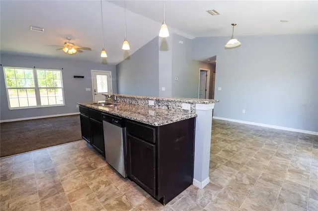 a kitchen with kitchen island granite countertop a sink and a stove