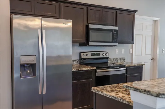 a kitchen with granite countertop a refrigerator and a stove top oven