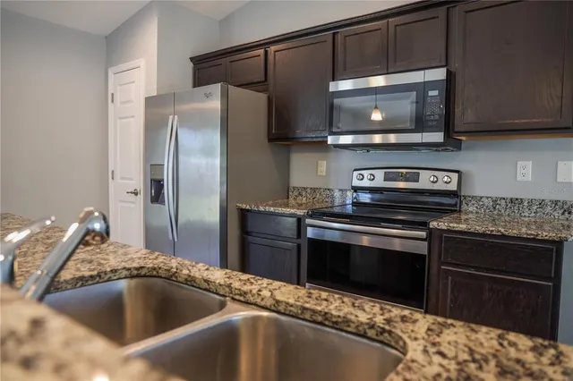 a kitchen with granite countertop a sink and stainless steel appliances