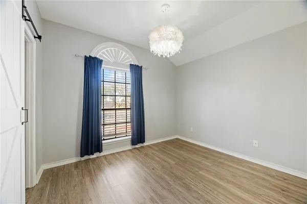 a view of an empty room with wooden floor and fan
