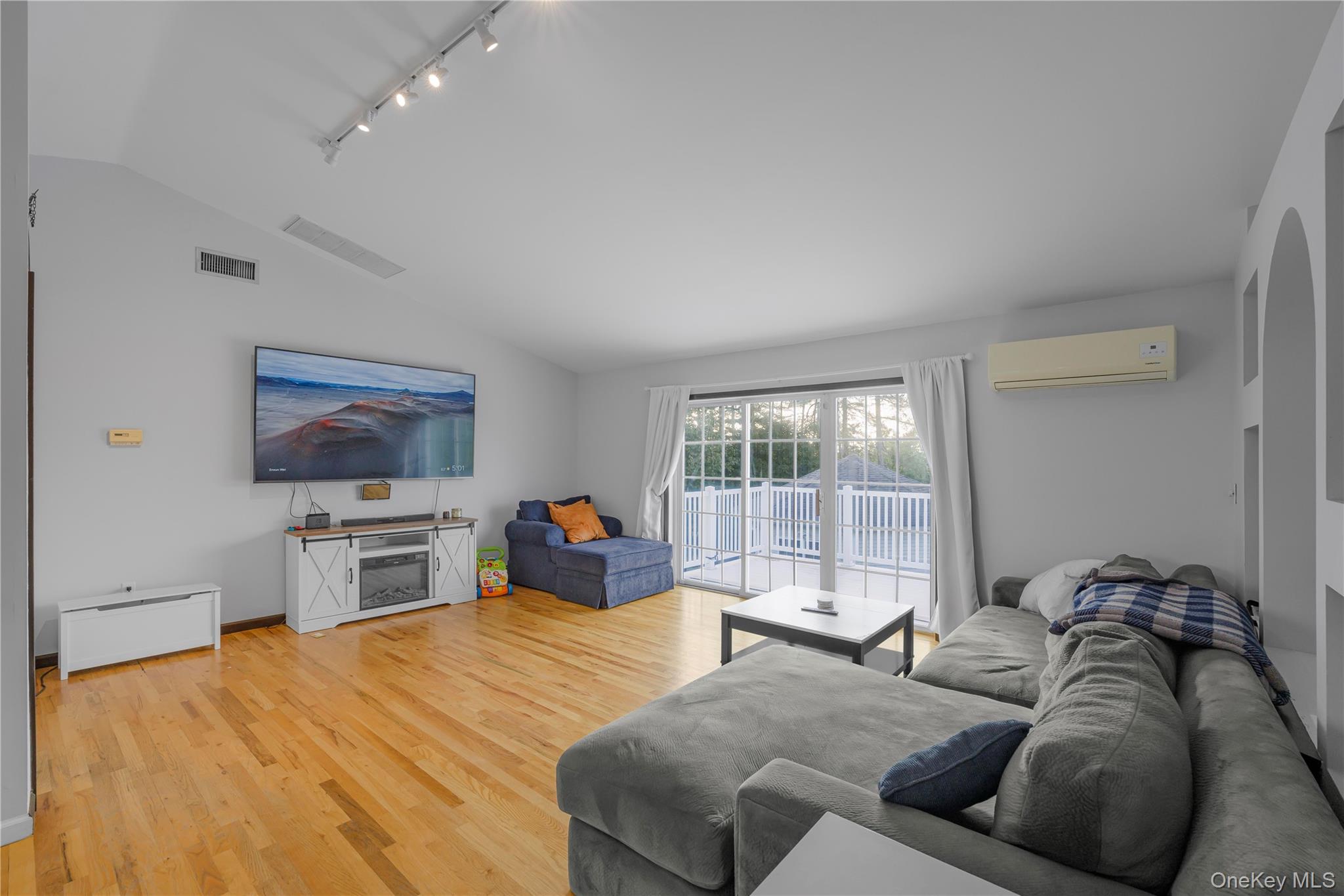 17 Brendella Court Wallkill, NY 12589 - Photo 10 of 42 Living area with track lighting, lofted ceiling, light wood-style flooring, and a wall mounted AC