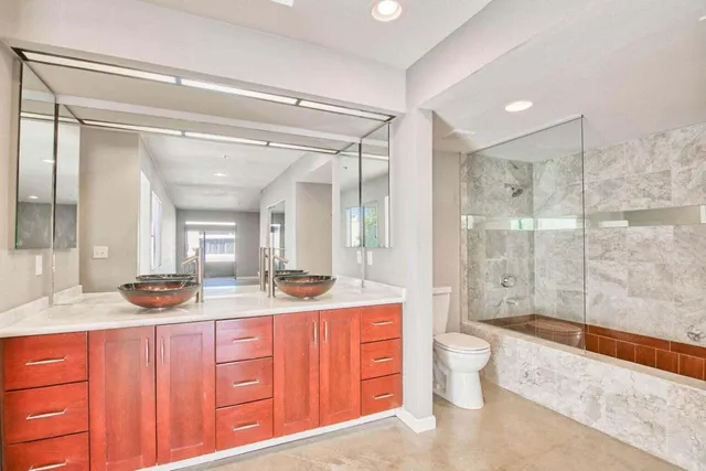 a spacious bathroom with a granite countertop sink toilet mirror and shower