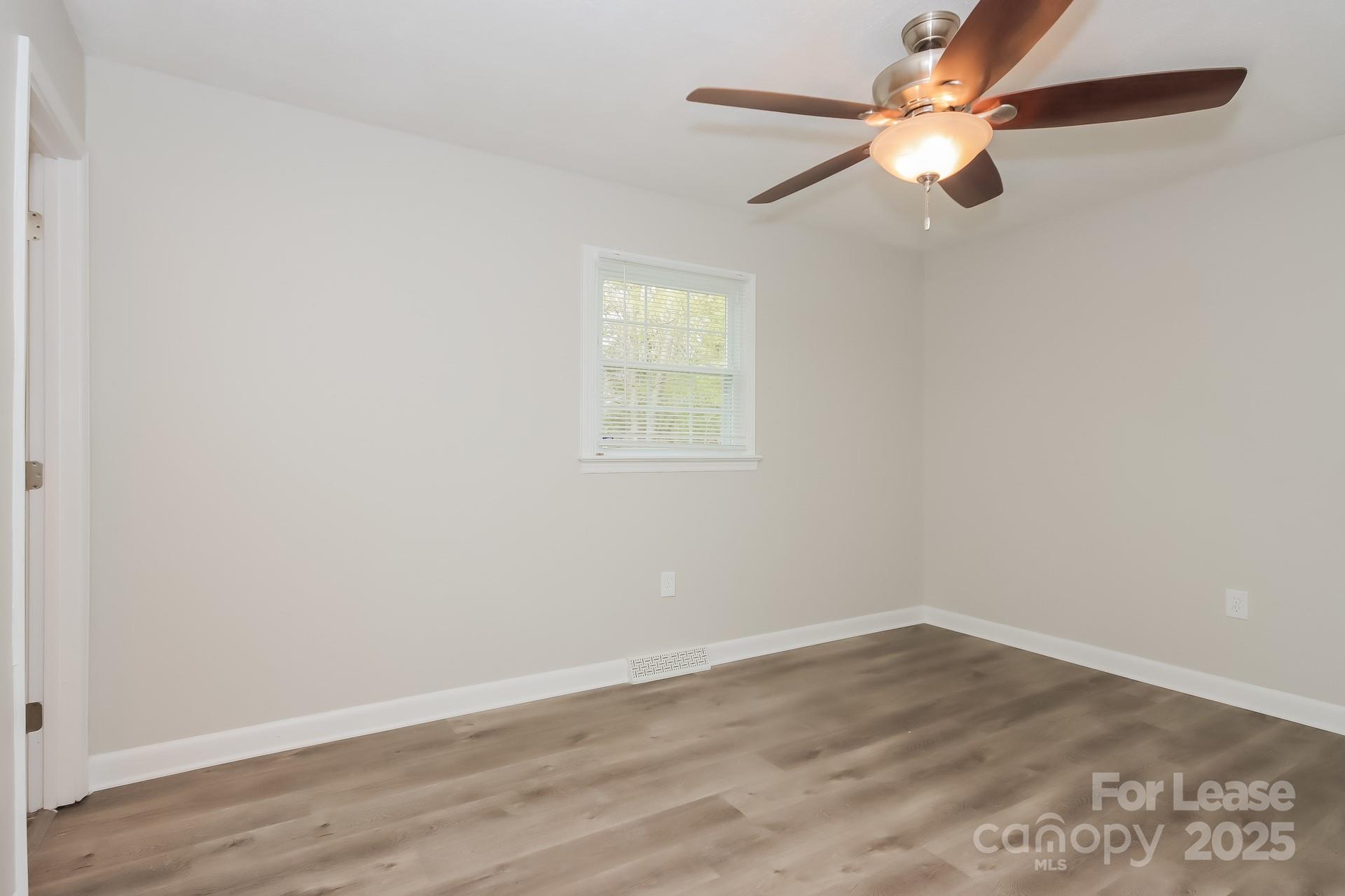 1135 Carolina Circle Statesville, NC 28677 - Photo 8 of 16 an empty room with wooden floor fan and windows