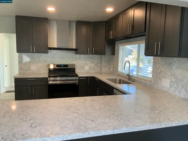 a kitchen with granite countertop a sink a stove and cabinets