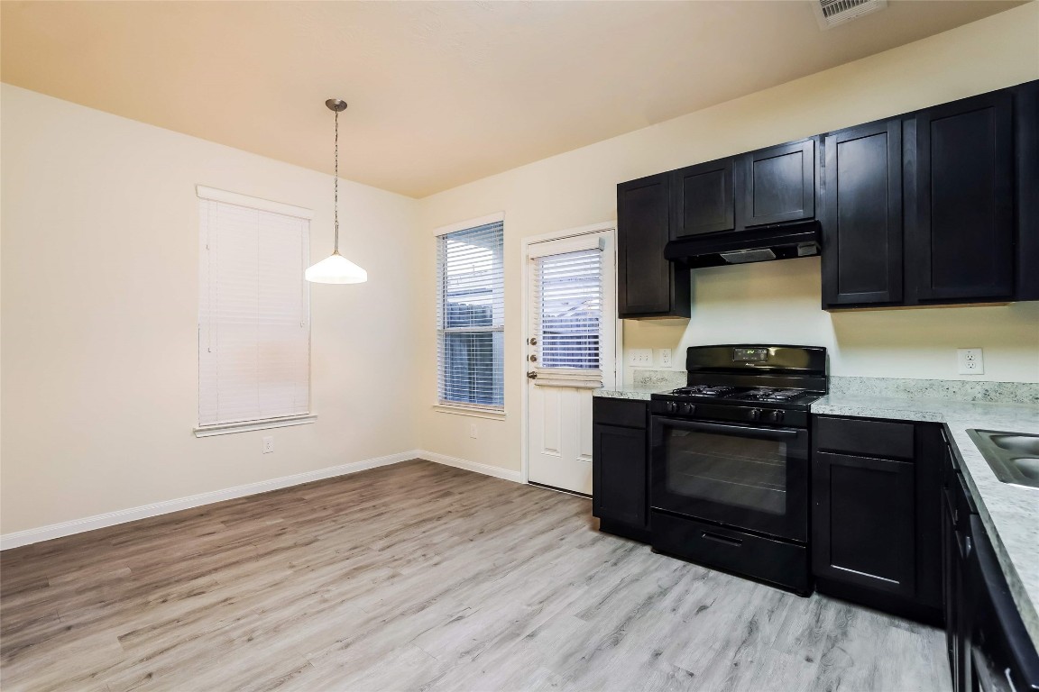 12330 Roy Mix Bohn Lane Houston, TX 77044 - Photo 5 of 17 a kitchen with granite countertop wooden cabinets and black appliances