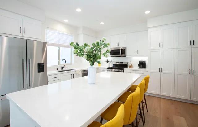 a living room with stainless steel appliances kitchen island granite countertop a dining table chairs refrigerator and cabinets